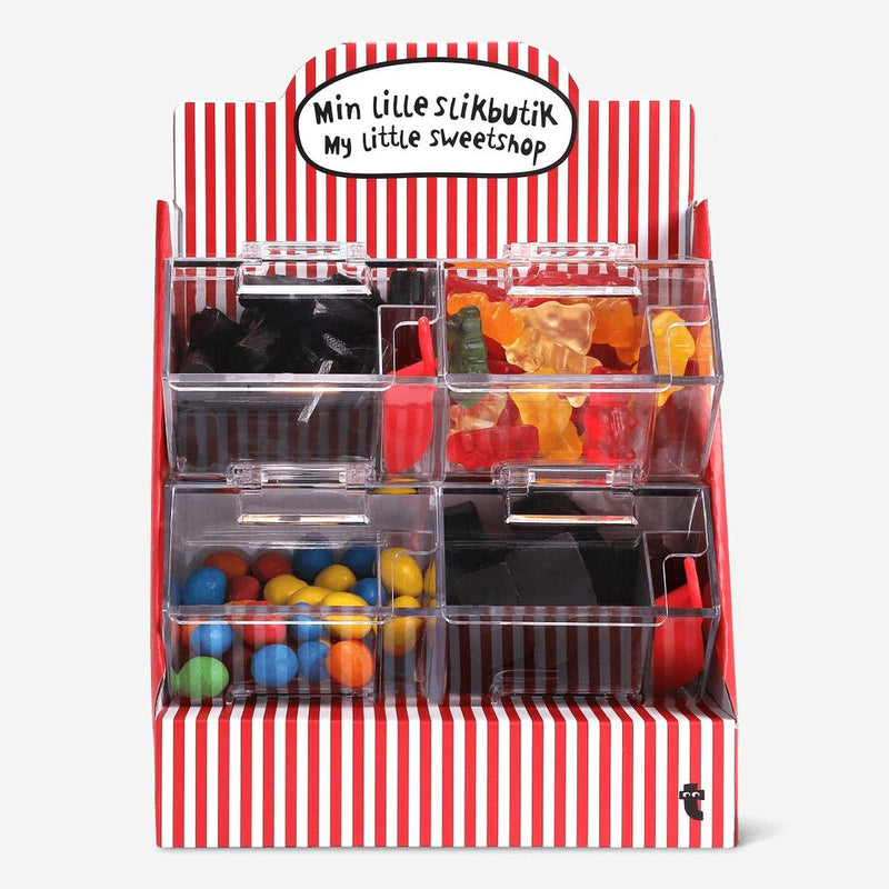 Mini toy sweetshop display with six clear compartments filled with colourful candies, including gummy bears, licorice, and chocolate-coated sweets, in a red and white striped stand labeled "My little sweetshop